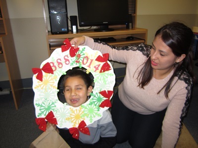 a child sticking her face out of a Christmas Wreath